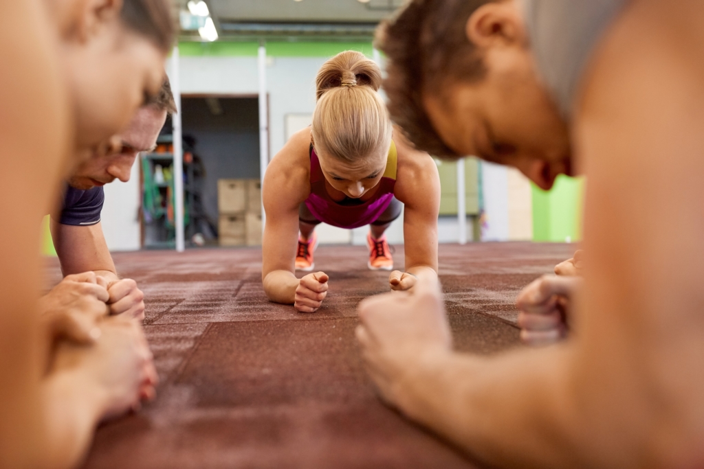 group of people doing plank exercise in gym